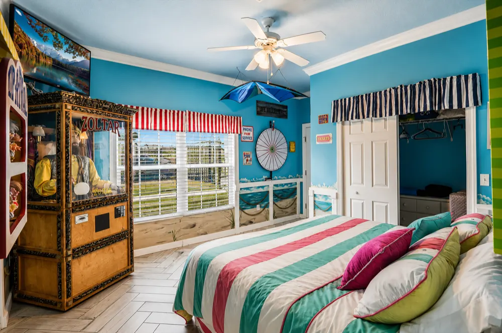 Carnival Games Waterfront Suite at Great Escape Lakeside: the Zoltar cabinet, a striped awning over the lake-view window, the prize wheel and the striped king bed