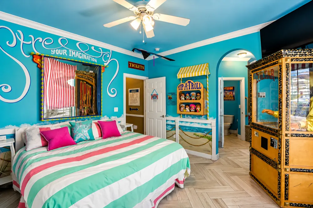 Carnival Games suite: the funhouse stretch mirror over the king bed under Stretch Your Imagination, the Tip-A-Troll booth, the TICKETS sign and the Zoltar cabinet