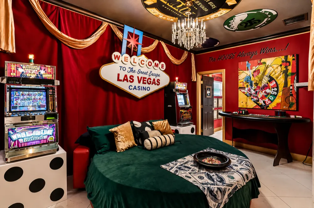 The Casino Games Suite at Great Escape Lakeside: a Welcome To The Great Escape Las Vegas Casino sign over a round king bed, slot machines either side, giant dice nightstands