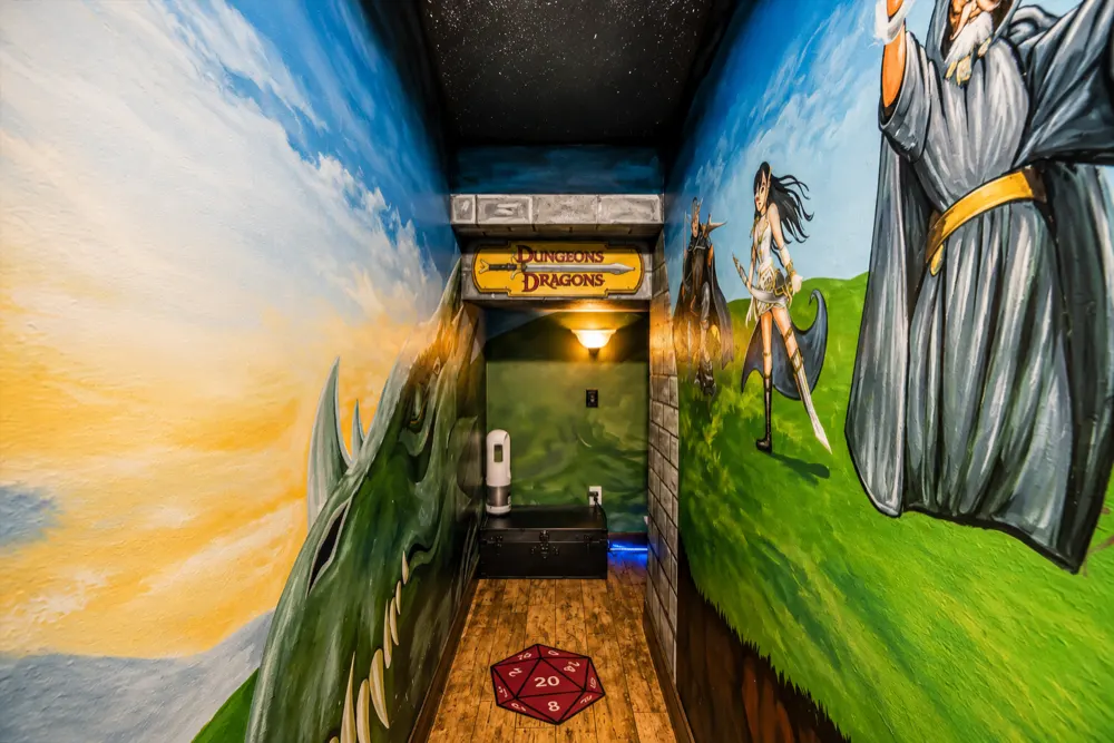 The Dungeons and Dragons corridor from the doorway: the sword sign over the arch, the d20 rug, the trunk, the dragon on the left wall and the wizard on the right