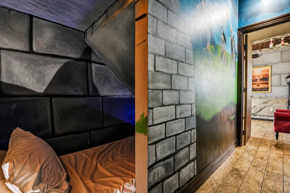 The Dungeons and Dragons room from the hall: stone-block walls, the bed nook on the left, the hallway and a red chair beyond the door