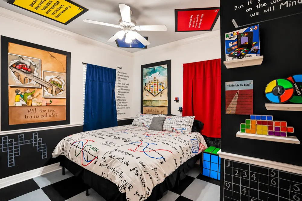 Mind Games bedroom at Great Escape Lakeside: a king bed with equation-print bedding, chalkboard walls with sudoku grids, Escher paintings, a Tetris and Simon shelf and crossword clues by the closet