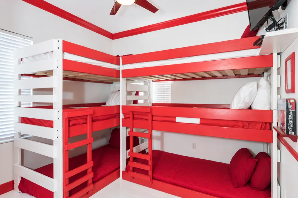 Giant Operation bedroom at Great Escape Lakeside: two red and white triple bunk beds under red crown molding, a TV in the corner