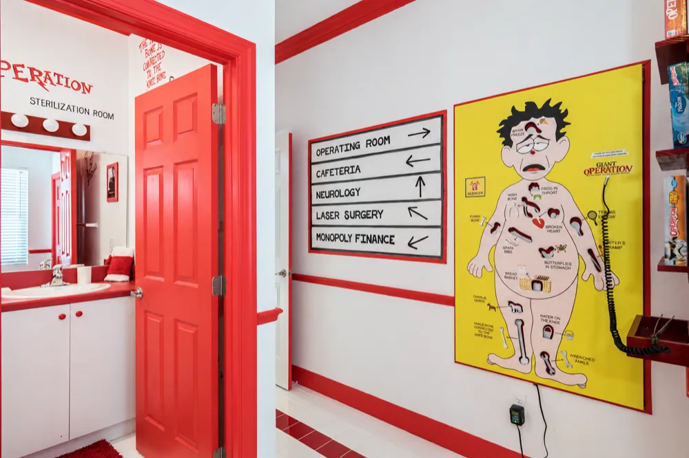The Operation room hallway: the Sterilization Room door, hospital direction signs and the yellow life-sized Operation board with tweezers on a cord
