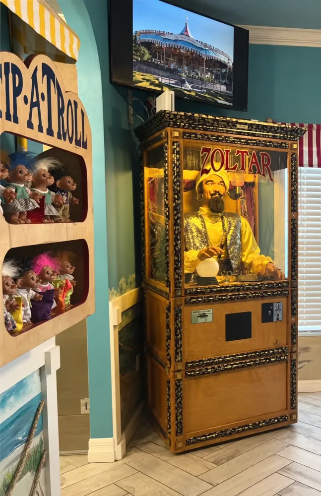 Zoltar fortune teller cabinet beside the Tip-A-Troll booth in the Carnival Games suite