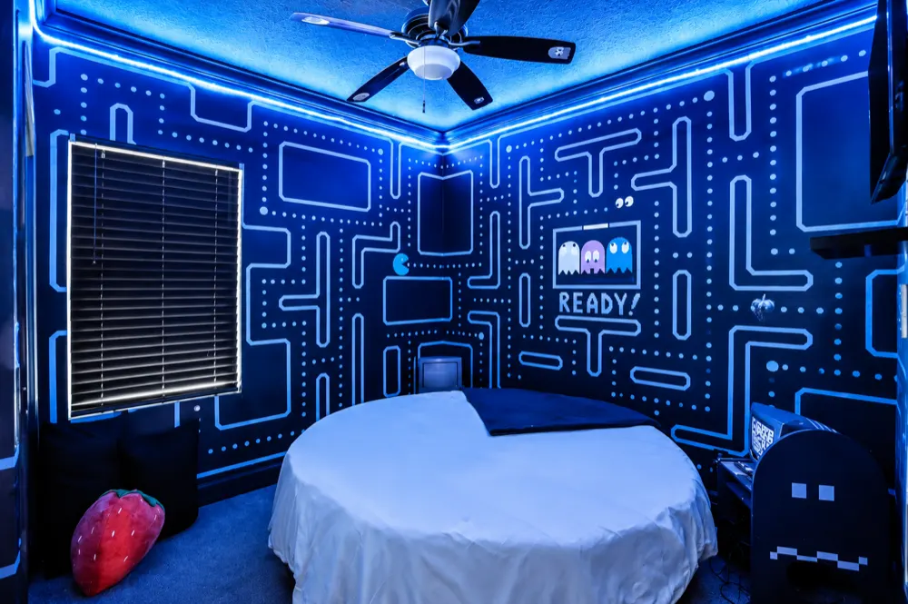 The Pac-Man bedroom at Great Escape Lakeside: a round bed under a neon maze painted across every wall, READY! and the four ghosts above the headboard