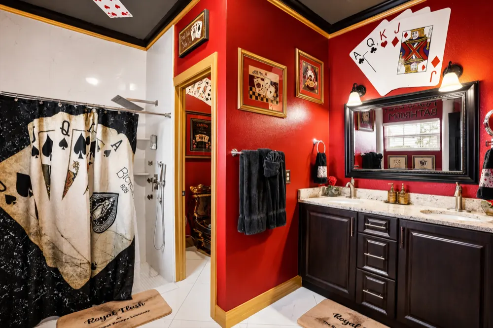 The Royal Flush bath: a playing-card shower curtain, giant cards over the double granite vanity, the walk-in shower and the gold toilet behind the door