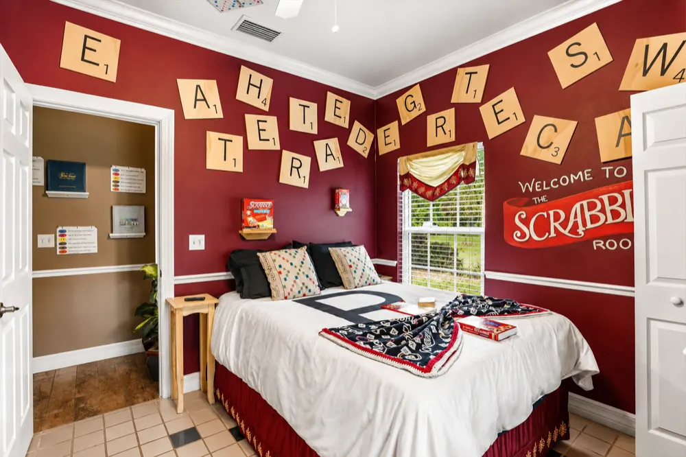 The Scrabble bedroom: giant letter tiles over the queen bed, a Scrabble-print throw, the open door to the Jack-n-Jill bath