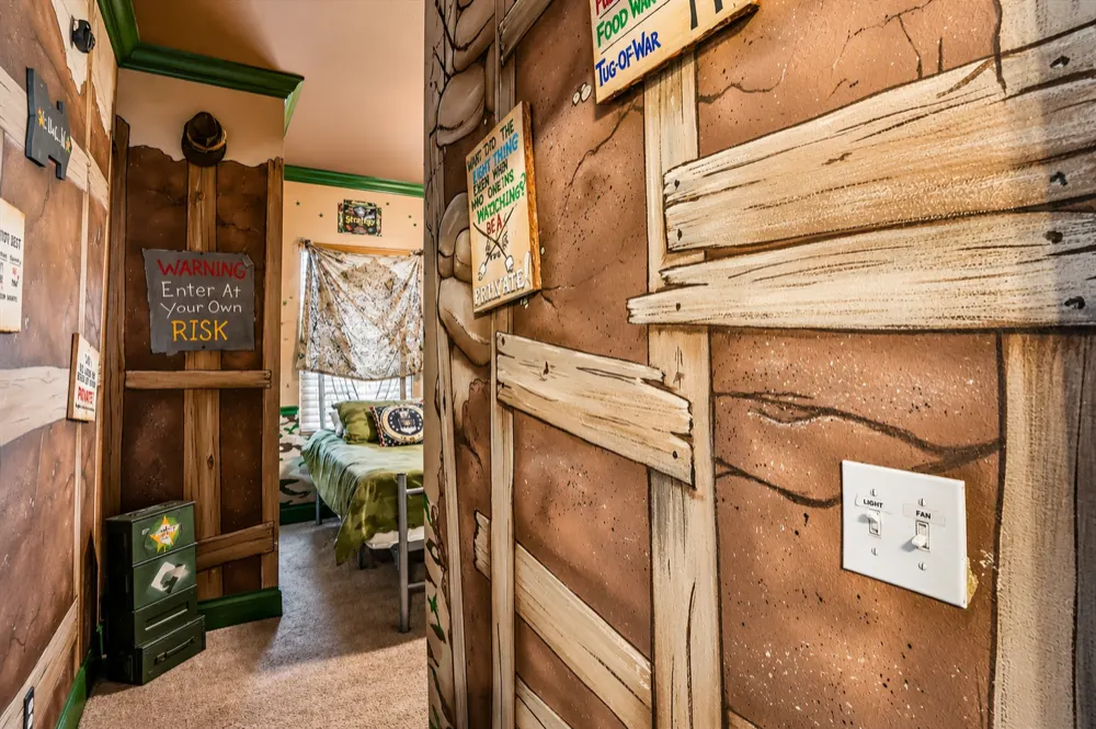 The hallway into the War Games room painted as a trench: sandbags, timber shoring, the Warning Enter At Your Own Risk sign and an ammo box